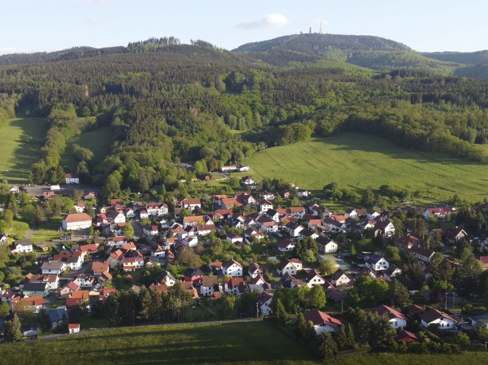 Un village rural où les maisons sont regroupées, entouré de champs verdoyants et de collines.