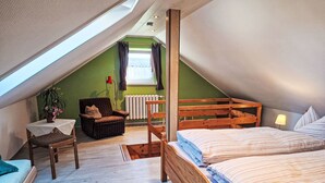 A bedroom with a sloped ceiling, a wooden bed, a chair, a small table with a plant, and a radiator. - Vacation home Ziller by Interhome (Crottendorf)