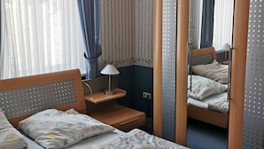 Ein Schlafzimmer mit einem großen Bett, einem Nachttisch mit Lampe, einem Spiegel und einem Kleiderschrank.