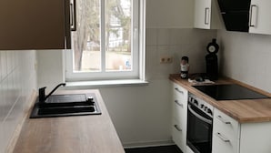 Eine moderne Küche mit Holzarbeitsplatte, weißen Schränken, einem Einbauofen und einem Fenster für natürliches Licht.