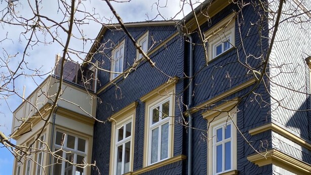 Ein mehrstöckiges Gebäude mit dunkler Fassade und gelbem Zierdekor.