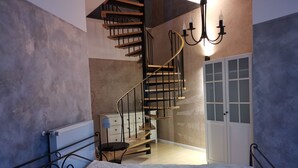 Ein Schlafzimmer mit einem Bett, einem Schminktisch, einer Kommode, einer Wendeltreppe und einer Tür mit Milchglasfenstern.