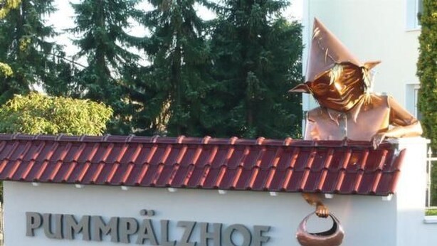 A building with a sign reading "PUMPÄLZHOF" and a sculpture of a figure on the roof. - in Witzelroda mit Grill und Garten by Interhome (Moorgrund)