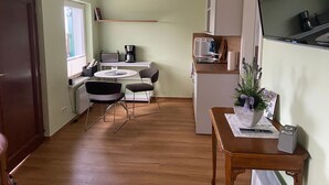A compact kitchen with a dining area, a small refrigerator, a coffee maker, and a TV.