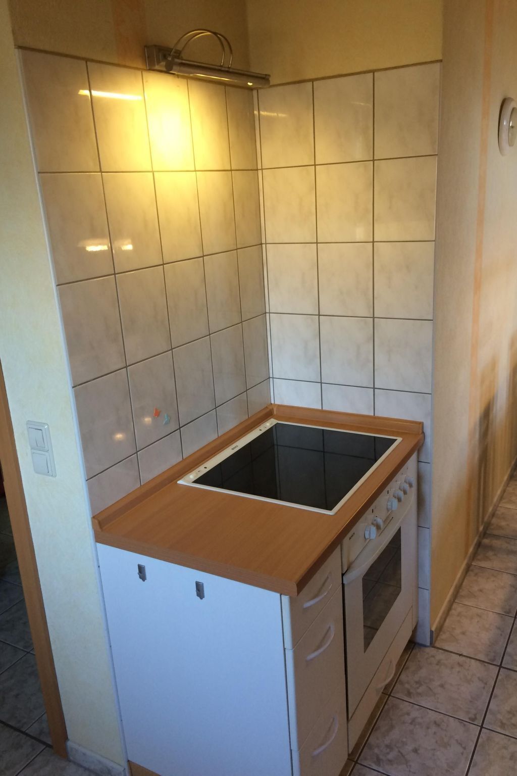 Una cocina compacta con estufa integrada, un refrigerador pequeño y un salpicadero de azulejos.