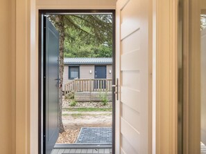 A doorway leading to a small wooden deck with a view of a house and trees. - Mobilheim mit Terrasse by Interhome (Lohmen)