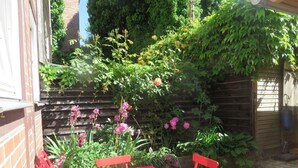 A red metal table and chairs set in a garden with a brick wall and wooden fence. - Appartement in Wismar mit Terrasse und Garten by Interhome (Wismar)