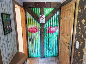 A room with a wooden door, a bench, and a wall with a floral pattern.