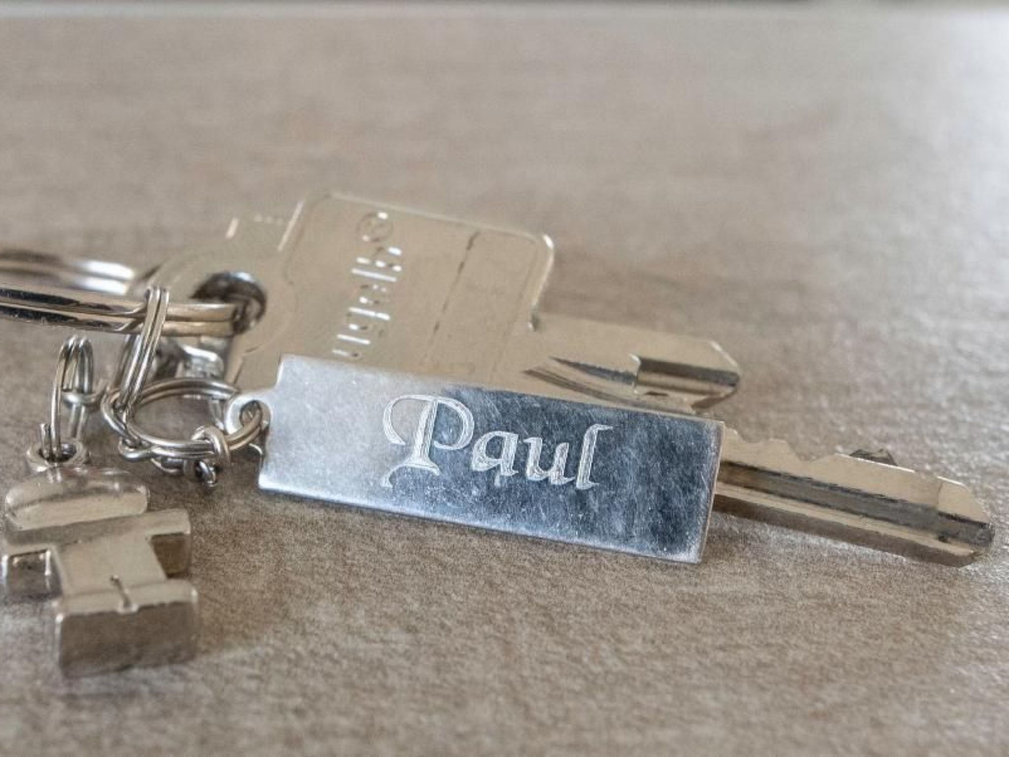 A set of keys with a keychain that has the name "Paul" engraved on it.