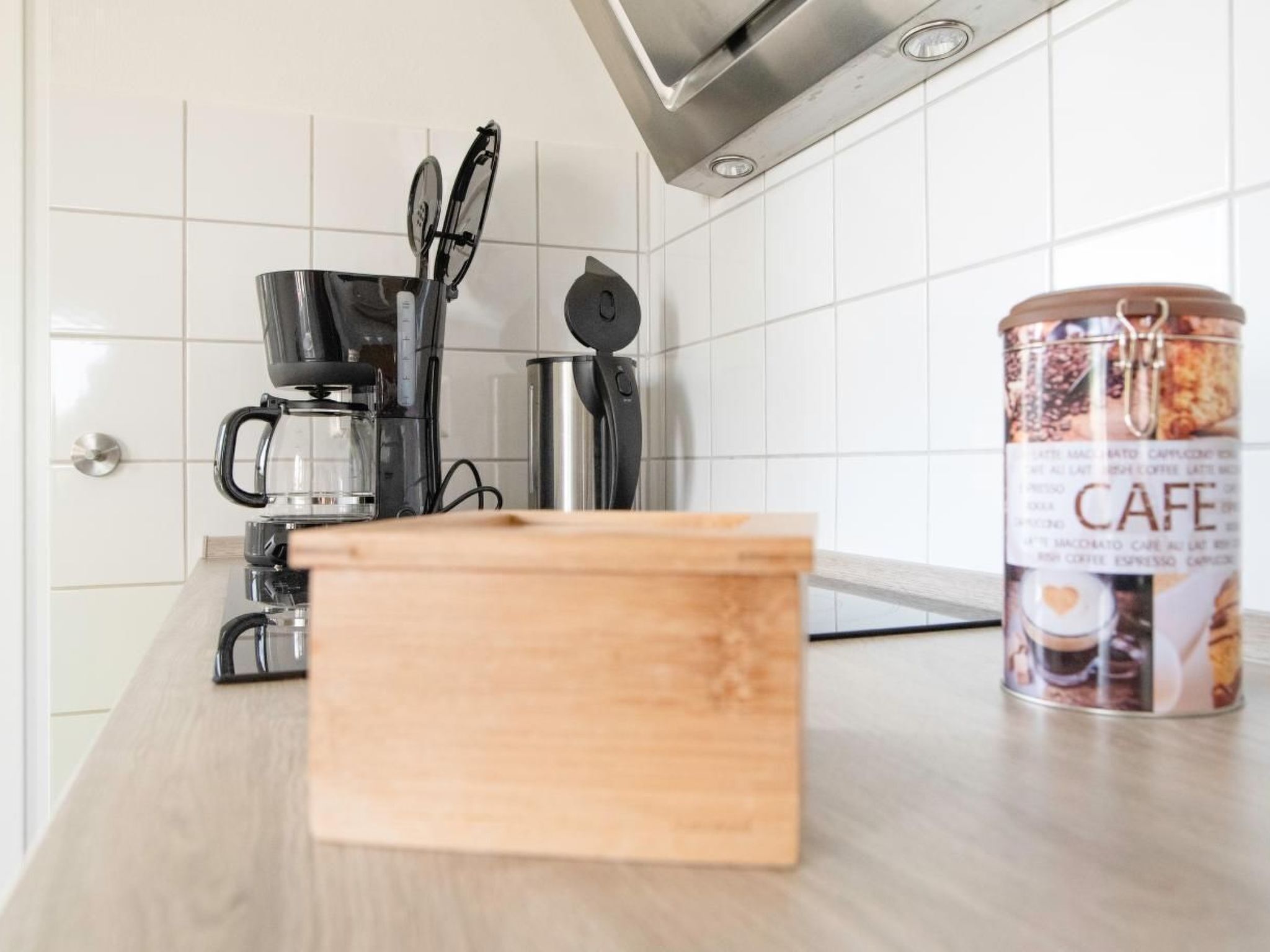 Une cuisine équipée d’une machine à café, d’une bouilloire et d’une boîte de café posée sur le comptoir.
