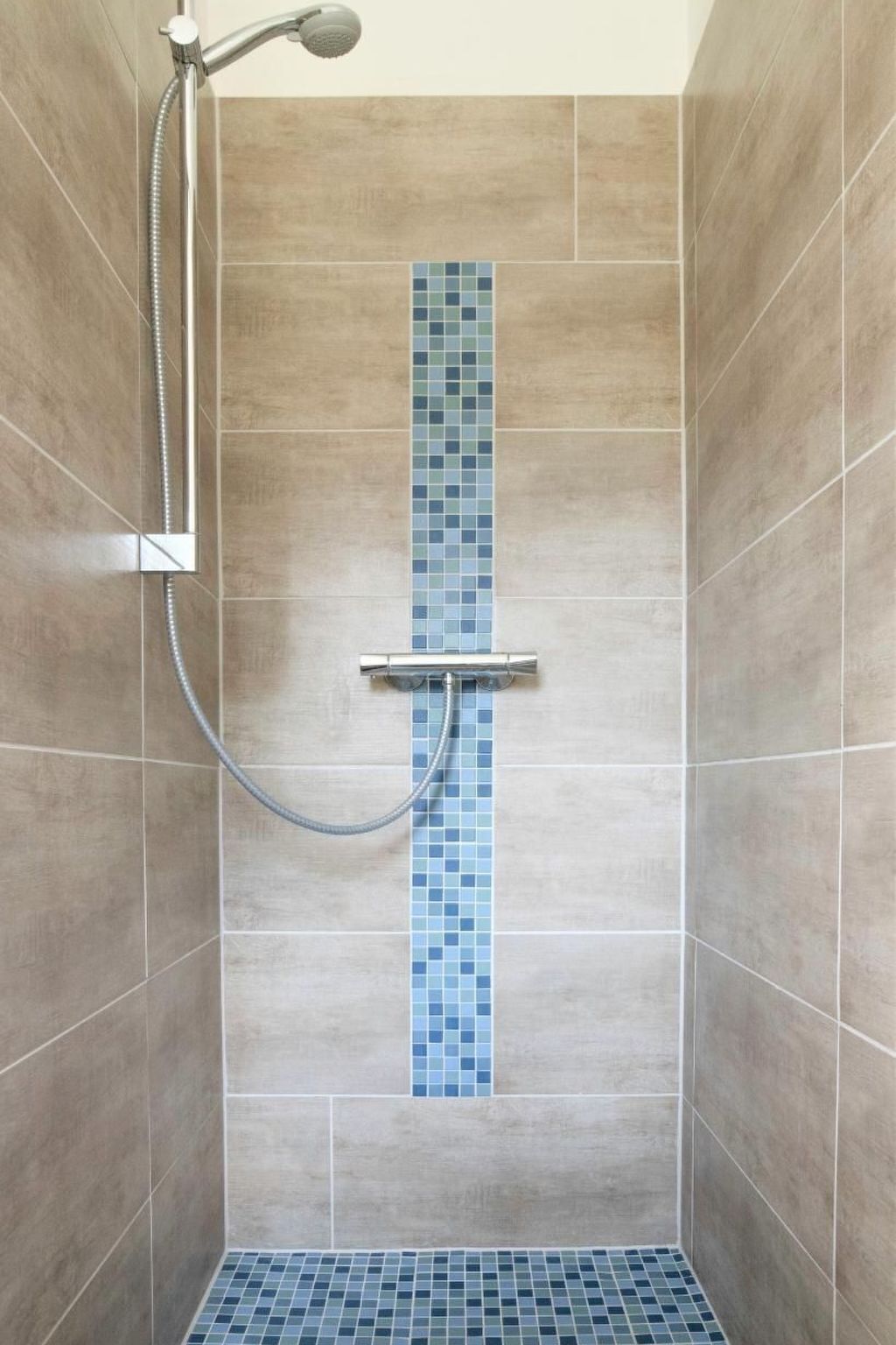 A shower with a vertical blue-tiled accent wall and a handheld showerhead.