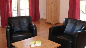 A room with two black leather chairs, a wooden table, and a wooden cabinet. - Wendorf by Interhome (Sanitz)