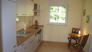 A compact kitchen with a window, a dining table with chairs, and a refrigerator. - Wendorf by Interhome (Sanitz)