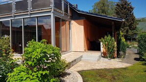 A modern house with large glass windows, a covered patio, and a well-maintained garden. - Waldperle by Interhome (Altwarp)