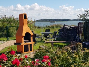 An outdoor patio with a brick oven, seating, and a view of a lake. - mit Whirlpool by Interhome (Altwarp)