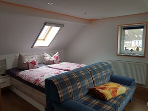 A bedroom with a bed, a window, a radiator, and a sofa. - mit Whirlpool by Interhome (Altwarp)