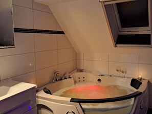 A modern bathroom with a freestanding bathtub, a vanity, and a window above the tub. - mit Whirlpool by Interhome (Altwarp)