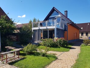 A two-story house with a balcony, a garden with a bench, and a paved pathway. - mit Whirlpool by Interhome (Altwarp)