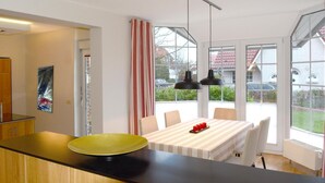 Eine moderne Küche mit Essbereich, großen Fenstern und Blick ins Freie.