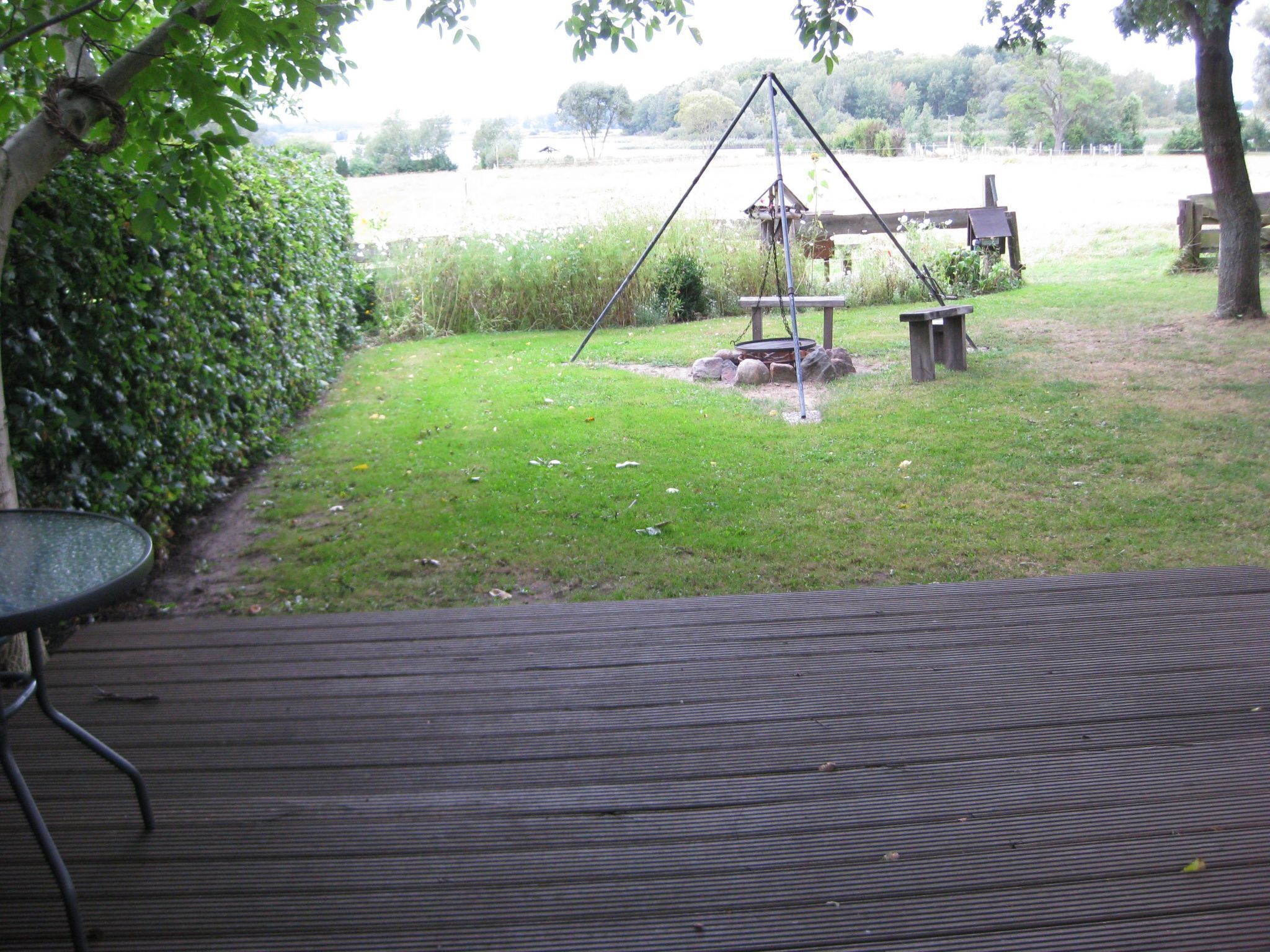 A wooden deck with a swing set and a small table.