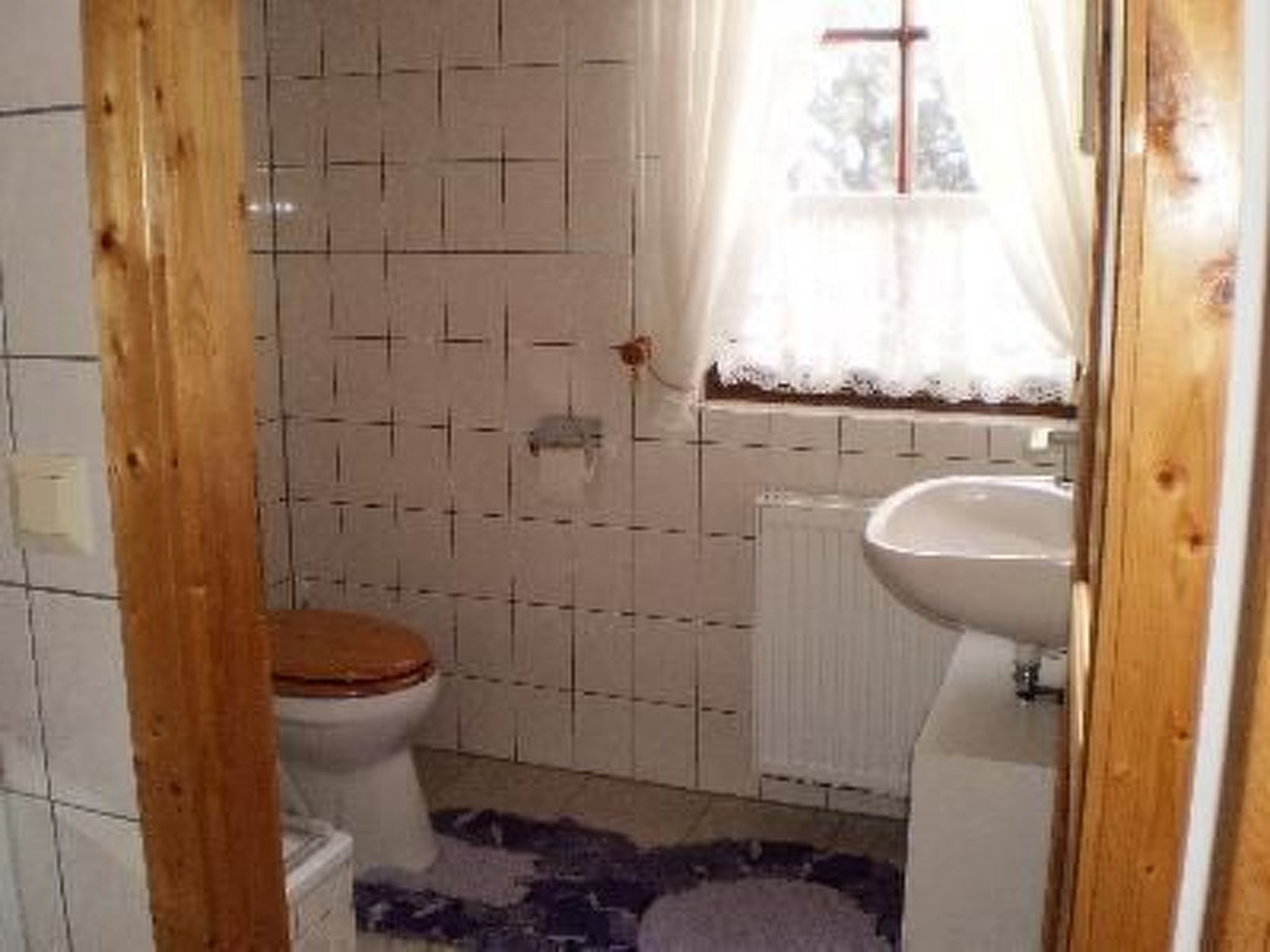 A bathroom with a toilet, sink, and tiled walls.