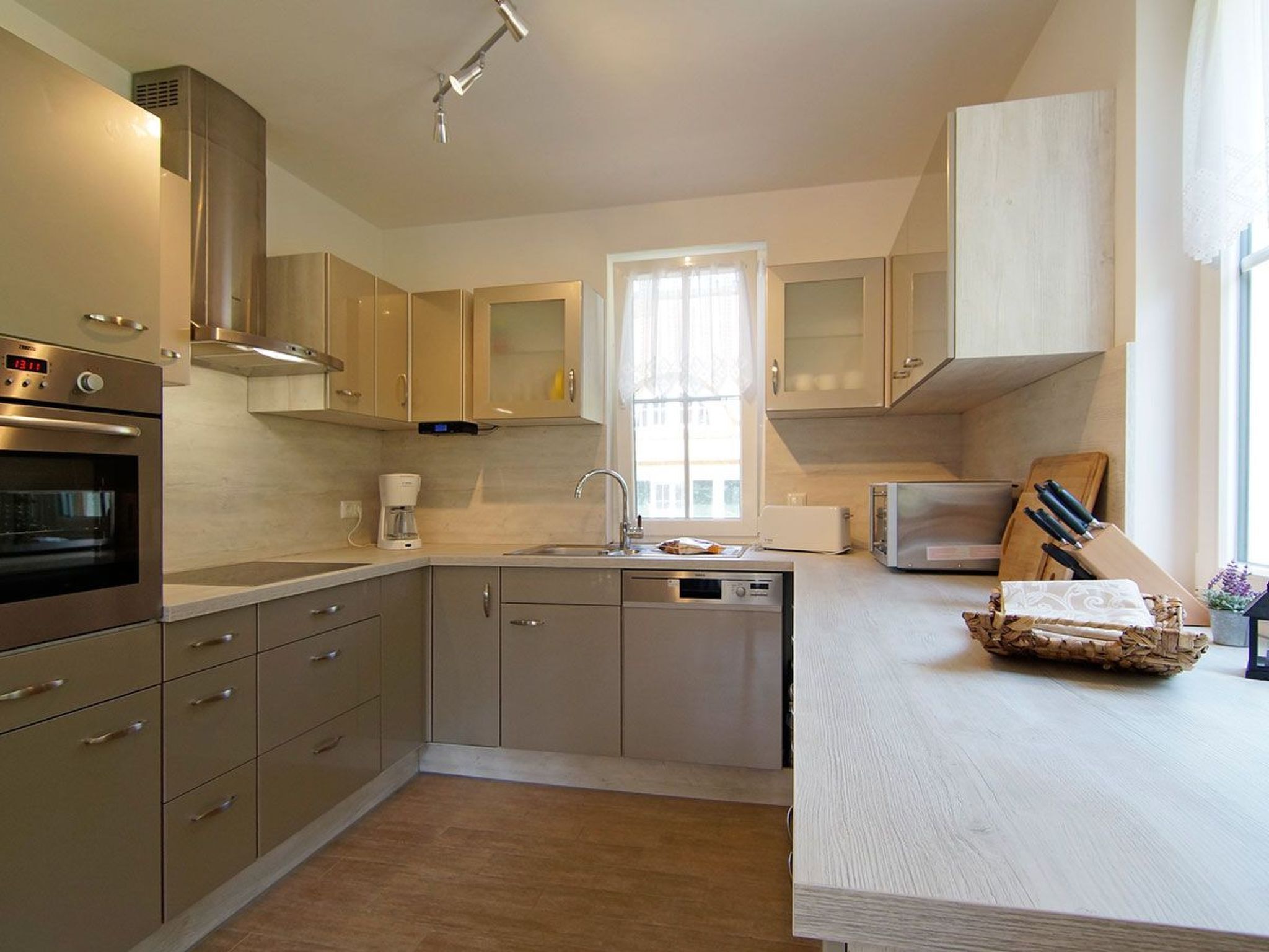 Una cocina moderna con electrodomésticos de acero inoxidable, lavavajillas integrado y un amplio ventanal que proporciona luz natural.