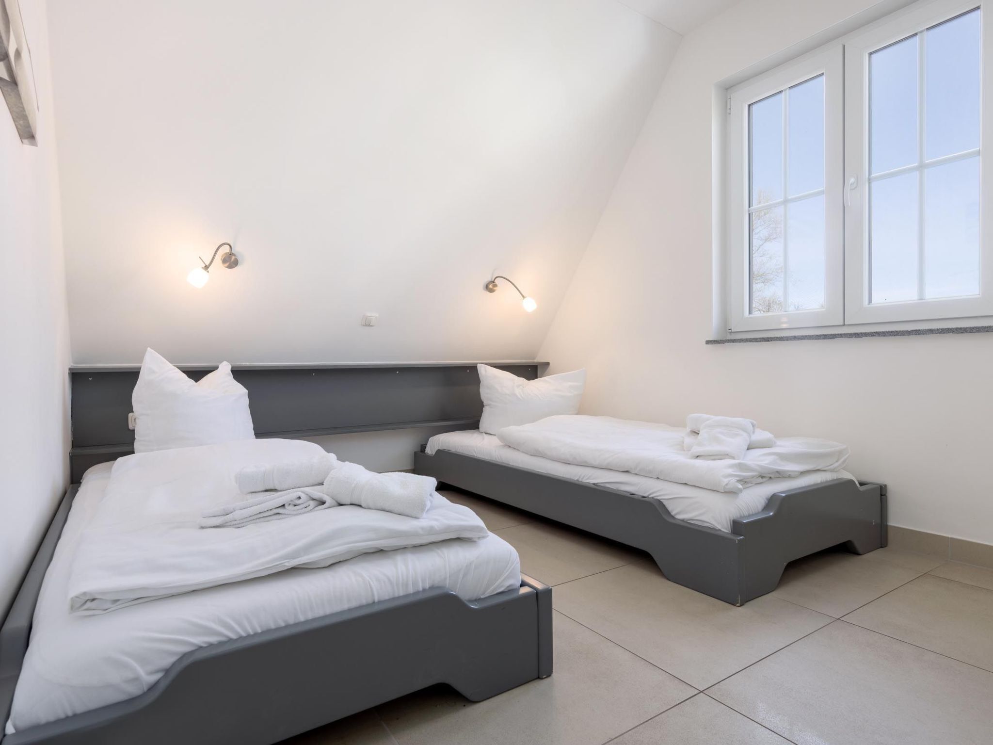 Un dormitorio con dos camas, techo inclinado y una ventana.