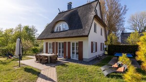 A house with a thatched roof, a patio with outdoor furniture, and a well-maintained garden. - Orchidee in Glowe by Interhome (Glowe)