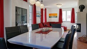 Un espace de salle à manger moderne, avec une grande table, des rideaux rouges et une cheminée.