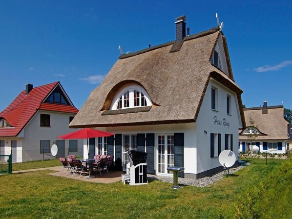 A traditional house with a thatched roof, a patio with outdoor seating, and satellite dishes. - Reethaus Romy in Glowe by Interhome (Glowe)