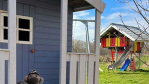 Een poppenhuis met een klein raam en een bankje.