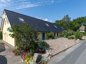 A single-story house with a dark tiled roof, a blue door, and a small garden with pink flowers and a tree. - im idyllischsten Winkel Rügens by Interhome (Gingst)