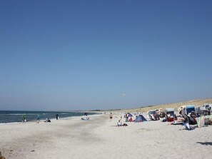A beach with tents and beach chairs, a clear sky, and the ocean in the background. - Vacation home Haus2 by Interhome (Neuendorf)