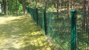 A pathway bordered by a green metal fence, surrounded by trees and grass. - Appartement mit Garten, Grill und Terrasse by Interhome (Ferchesar)
