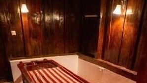 Una habitación con un banco de madera, una mesita y una alfombra roja.