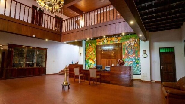 A spacious lobby with a high ceiling, wooden flooring, a reception desk, and a staircase leading to an upper level. - Kumarakom Heritage Resort & Ayurveda  (Vaikom)