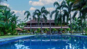 A pool with a reflection of a building surrounded by palm trees. - Kumarakom Heritage Resort & Ayurveda  (Vaikom)