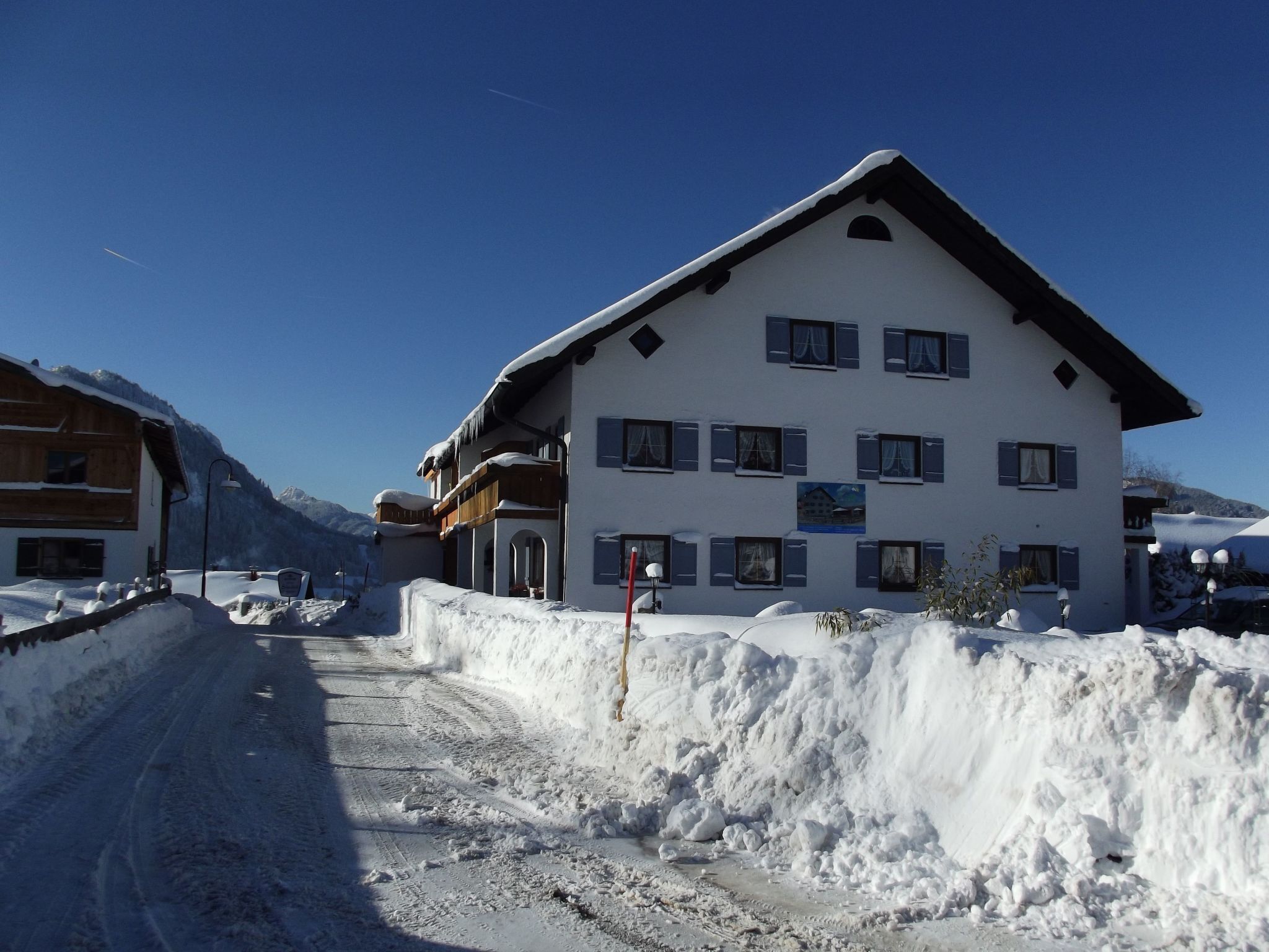 Ein mehrstöckiges Gebäude mit geneigtem Dach, großen Fenstern und einer schneebedeckten Fassade.