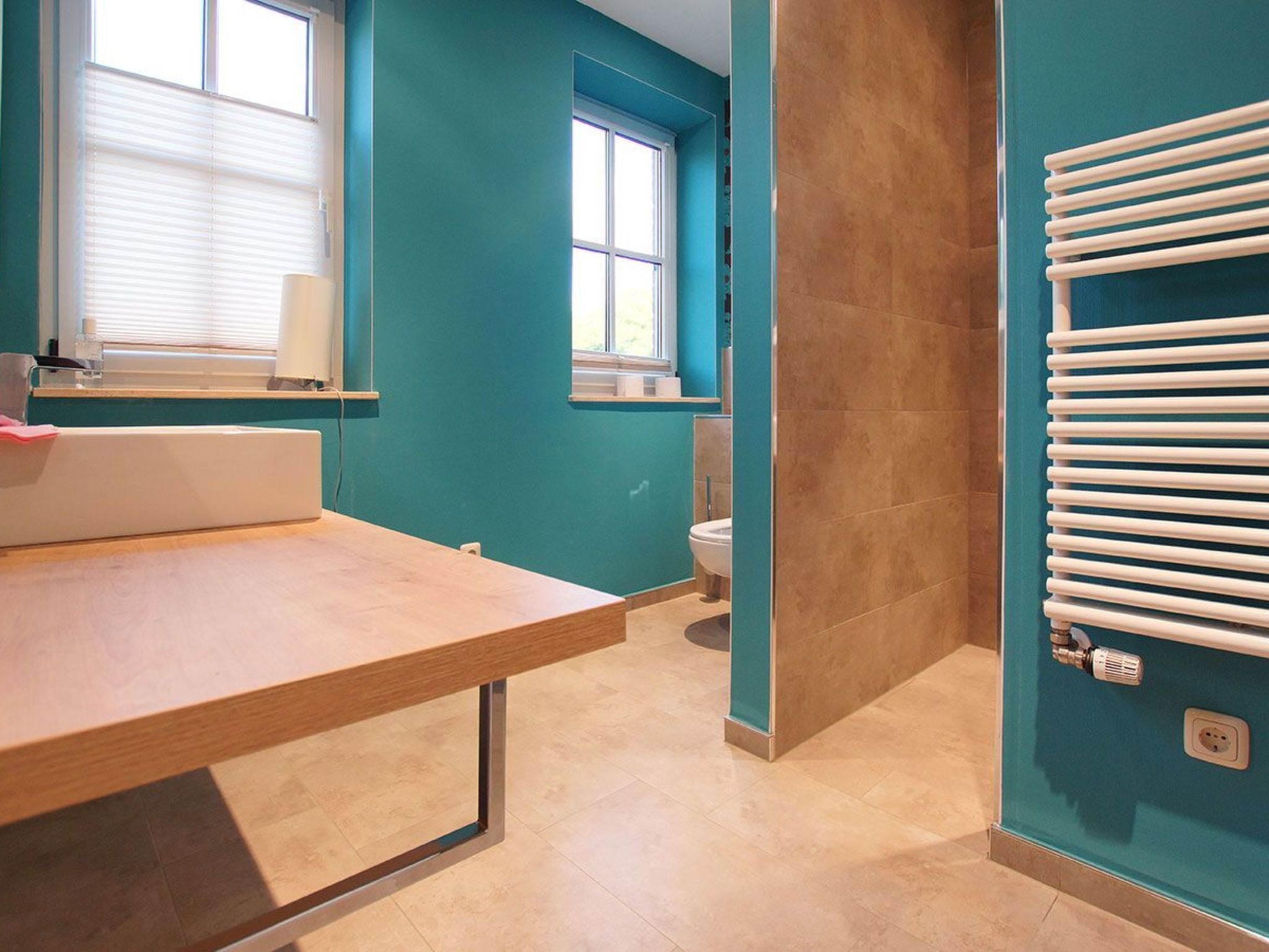 Une salle de bain moderne avec un meuble-lavabo en bois, une baignoire blanche et un radiateur encastré.