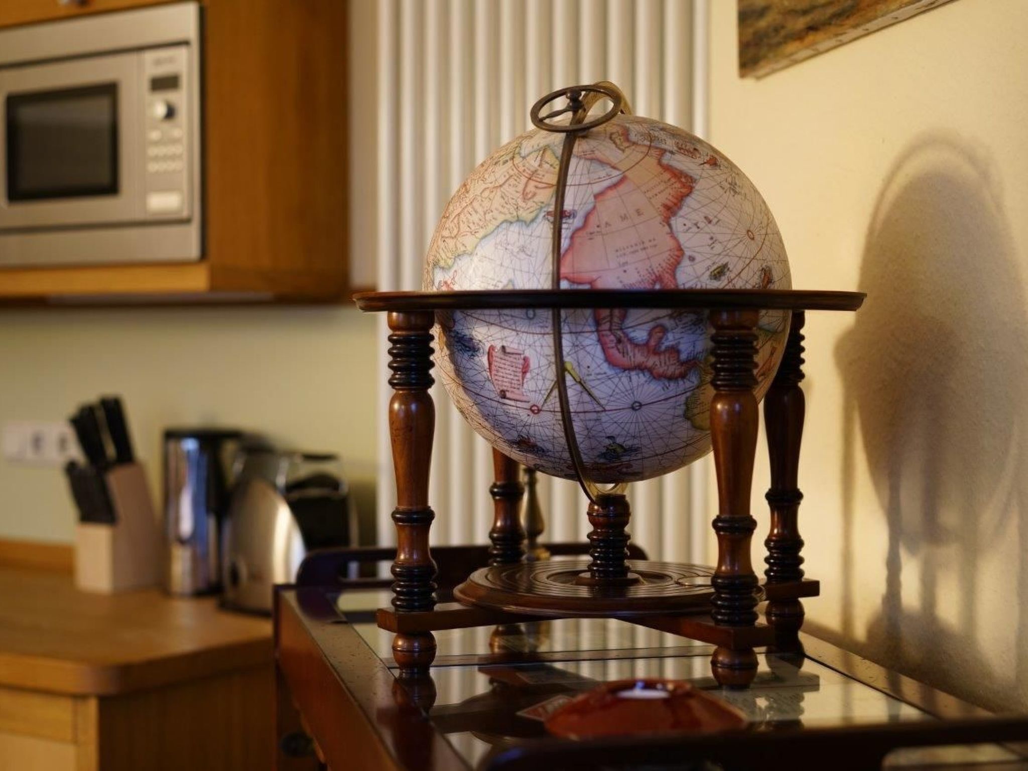 Un globe terrestre posé sur un support en bois, dans une cuisine.