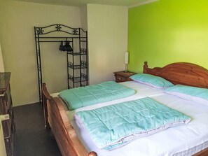 Ein Schlafzimmer mit einem Bett, einem Holzkopfteil, einem Nachttisch, einer Lampe und einem Metallregal.