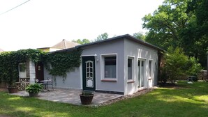 Un petit bâtiment d’un seul étage, doté d’une porte vert foncé, de fenêtres à cadre blanc et d’une terrasse carrelée.
