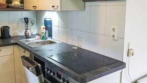 Une cuisine compacte dotée d’un four encastré, d’une plaque de cuisson et d’un évier.