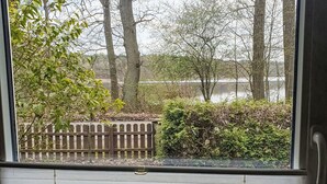 Une pièce dotée d’une fenêtre donnant sur un jardin clos, avec des arbres et un plan d’eau.