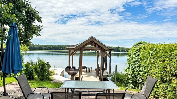 Ein Pavillon mit Tisch und Stühlen mit Blick auf einen See.