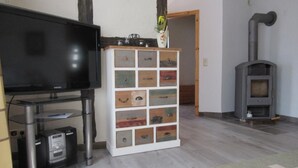 A living room with a flat-screen TV, a white cabinet with drawers, a fireplace, and a TV stand with electronic devices.