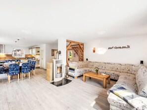 Un soggiorno moderno con camino, una zona pranzo con sedie blu e un divano con decorazioni a tema nautico.