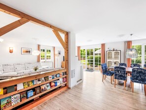 Un soggiorno moderno con una libreria in legno, un divano e un'area pranzo con sedie blu.