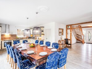 Una cucina moderna con zona pranzo, una scala in legno e vista sull'esterno.