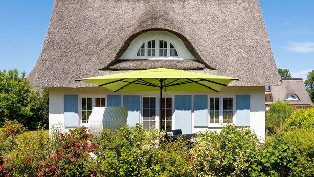 A house with a thatched roof, a large green umbrella, and a white exterior. - Marvin in Beckerwitz by Interhome (Alt Jassewitz)